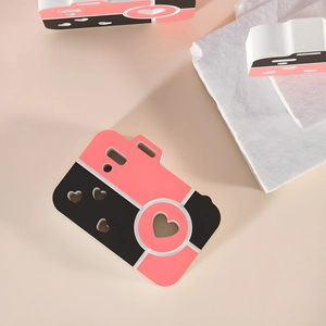 Pink camera-shaped DIY silicone mold with heart cutout design on pink textured stone
