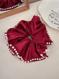 Close-up of burgundy satin oversized scrunchie with white pearl trim on its edges