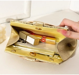 Close-up of golden evening clutch interior showing compact storage for lipstick and essentials