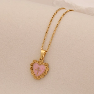 Detail of vintage heart pendant with pink enamel and gold cross on a delicate chain