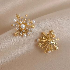 Detailed close-up of golden fireworks stud earrings with pearls and crystals on satin