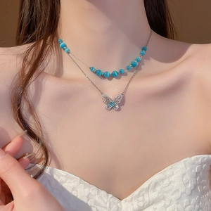 Detailed view of a double-layer necklace with blue cat-eye beads and zircon butterfly pendant