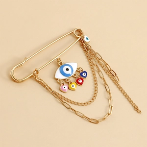 Detailed view of gold evil eye brooch with colorful heart charms and layered metal chain tassels