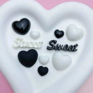 Detail of black and white resin heart charms and sweet letters for DIY crafts