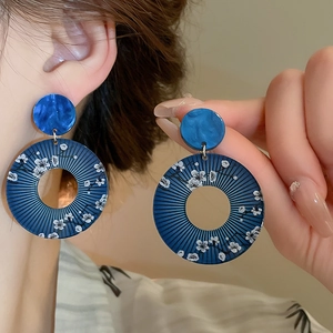 Detail of blue marble resin earrings with white plum blossom pattern on a hoop