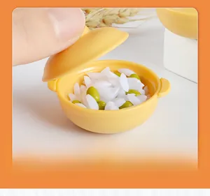 Close-up of a dollhouse miniature yellow clay pot model with realistic rice and peas