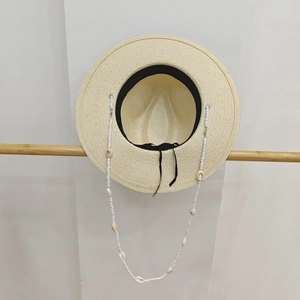Vintage beige straw hat with shell bead chain strap shown on a minimalist wooden hanger
