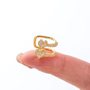 Close-up of a gold butterfly ear cuff with sparkling zircon hearts on a finger