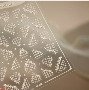 Detailed close-up of white lace grid nail stickers with 3D embossed texture and fan patterns