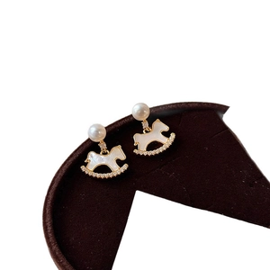 Gold plated rocking horse pearl earrings with sparkling zircon accents on display