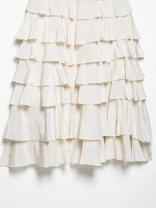 Detailansicht eines cremefarbenen Satin-Stufenkleids mit eleganten Lagen und weichem Glanz