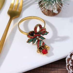 Close-up of golden Christmas napkin ring with rhinestone bow and bells on a plate
