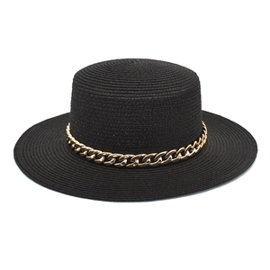 Détail d'un chapeau canotier noir à dessus plat avec chaîne décorative en acrylique doré