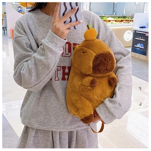 Cute Capybara plush backpack with orange decoration shown in a lifestyle mirror selfie