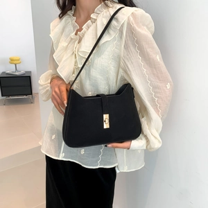 Retro black suede underarm bag with gold metal buckle shown in a stylish indoor setting