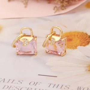 Macro detail of gold handbag earrings with pink square crystal and micro moon accent