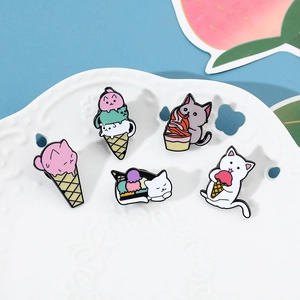 Macro shot of five colorful enamel cat and ice cream pins on a white ceramic plate