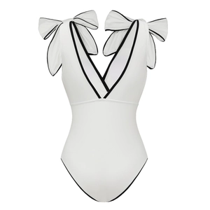 Flat lay of white one-piece swimsuit featuring black contrast trim and bow shoulder details