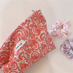 Detail of red floral cotton makeup bag with woven label and matching hair scrunchies