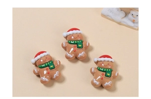 Three gingerbread man resin charms with red hats and green scarves for DIY crafts