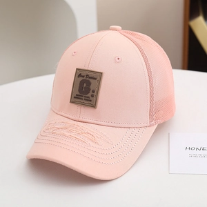 Dettaglio del cappellino trucker rosa con visiera usurata e toppa con lettera G