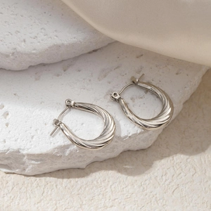 Detail view of silver twisted rope U-shaped earrings on stone and silk background
