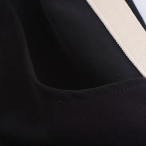 Detail of black woven fabric with off-white webbing and precision edge stitching