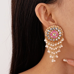 Elegant gold earrings with pink enamel flower, rhinestones and pearl tassels on a model