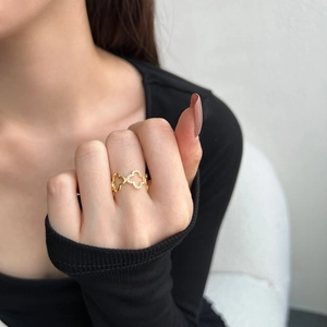 Detail showing gold clover ring with pavé-set zircons on a model's hand with soft lighting