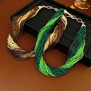 Detail view of multi-strand beaded necklaces in gold, green and brown on a jewelry stand