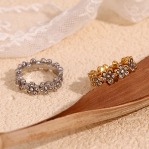 Détail de bagues fleurs en or et argent avec micro-pavé de cristaux sur une surface texturée