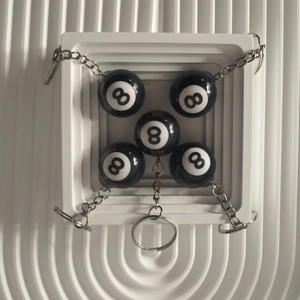 Macro detail of five black resin number 8 pool ball keychains in a white display tray