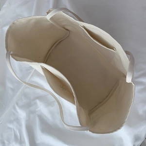 Spacious interior of off-white canvas tote bag with internal pocket and logo detail