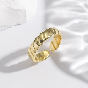 Adjustable gold plated copper ring with irregular twisted rope texture on a white stone background
