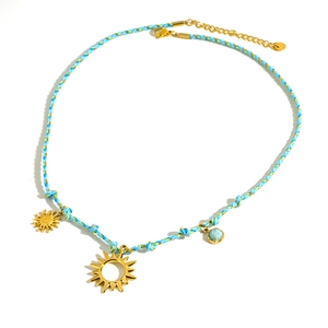 Collana artigianale in corda blu con ciondoli a sole dorati e gemma blu su bianco