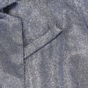 Macro detail of high-density sequin fabric on deep blue blazer with notched lapel