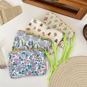 Detail view of floral and bear patterned canvas cosmetic bags with neon green tassels