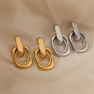 Gold and silver interlocking geometric link earrings on beige silk fabric background