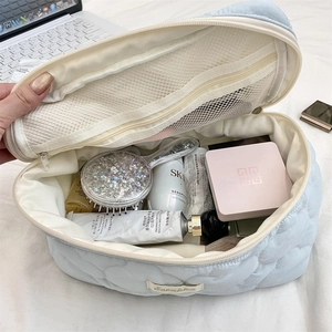 Detailed interior of quilted cosmetic bag showing spacious mesh pocket and makeup storage