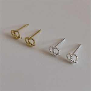 Detail of twisted rope knot stud earrings in polished gold and silver metallic finishes