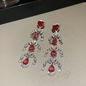 Detailed macro view of silver earrings with red heart stones and shimmering tassels