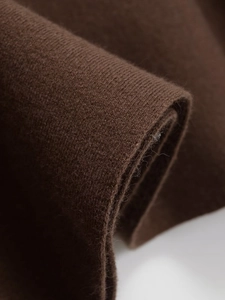 Macro shot of dark brown knitted fabric texture showing soft wool-like fibers and patterns