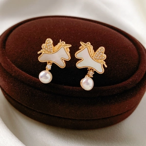 Gros plan de boucles d'oreilles licorne plaquées or 18k avec ailes en zircon et perles