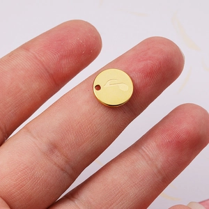 Polished 18K gold stainless steel round pendant with musical note engraving shown in hand