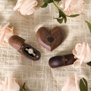 Handcrafted heart walnut ring box with a gold engagement ring on rustic linen fabric