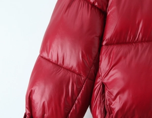 Detail of red glossy padded jacket featuring quilted texture and shiny finish material