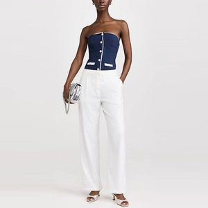 Navy blue strapless bustier top paired with white wide-leg trousers and a silver chain bag