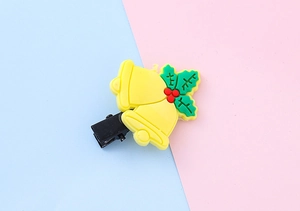 Close-up of a Christmas holly and bells hair clip on a pink and blue background
