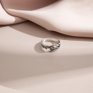 Detailed view of silver angel wing ring with intricate feather texture on neutral background