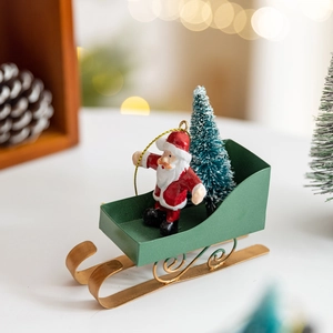 Red Santa Claus on green iron sleigh with Christmas tree festive desktop decoration